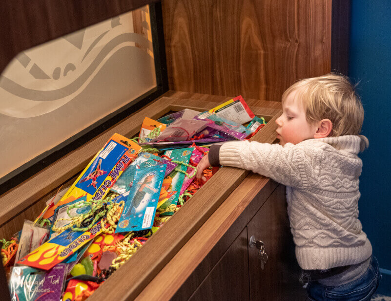 Small child choosing a toy out of Georgie's restaurants treasure box.