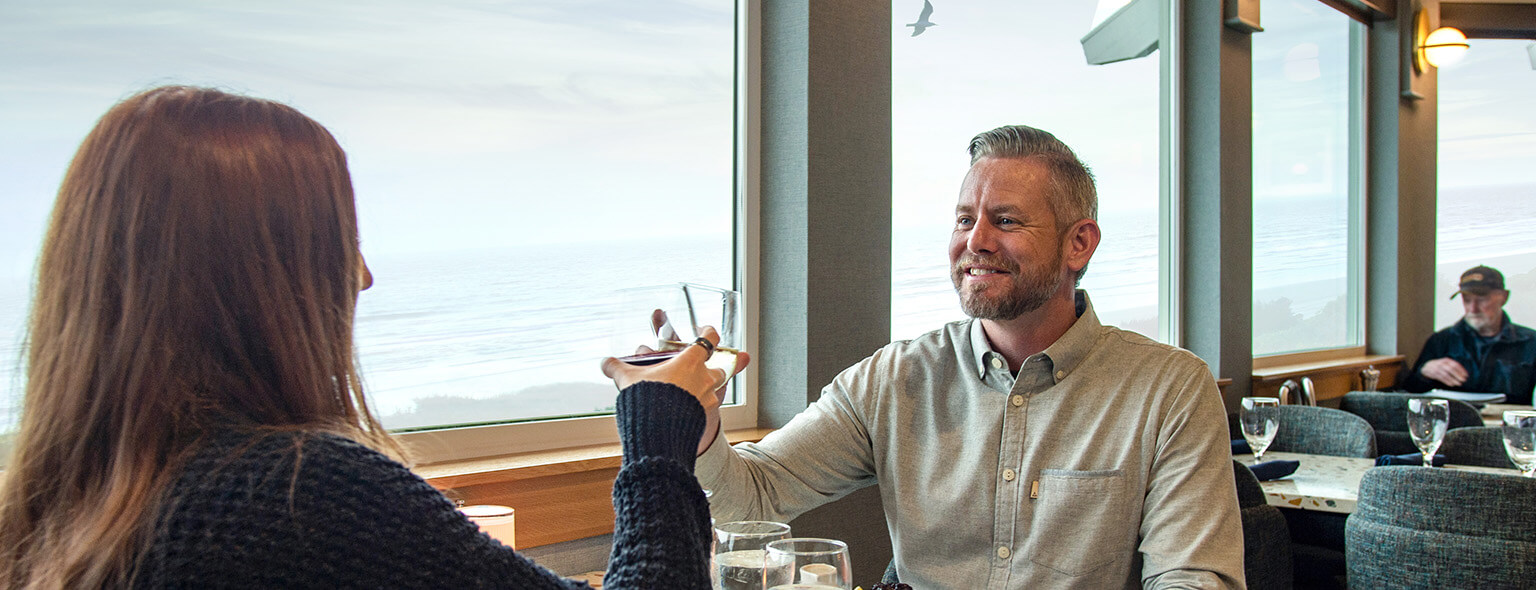 Couple raising a glass at Georgie's with a view of the Pacific ocean