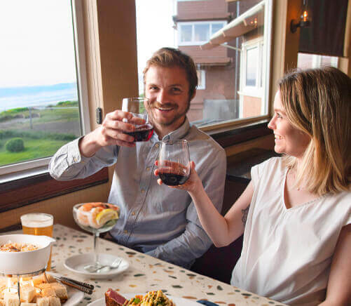 a couple celebrating at Georgie's with an ocean view and red wine