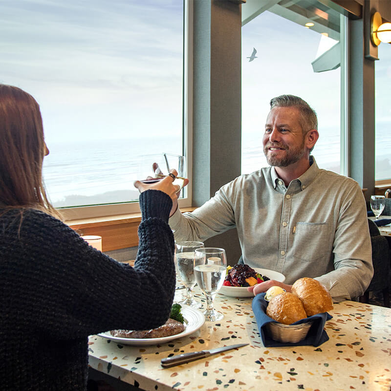 Couple raising a glass at Georgie's with a view of the Pacific ocean